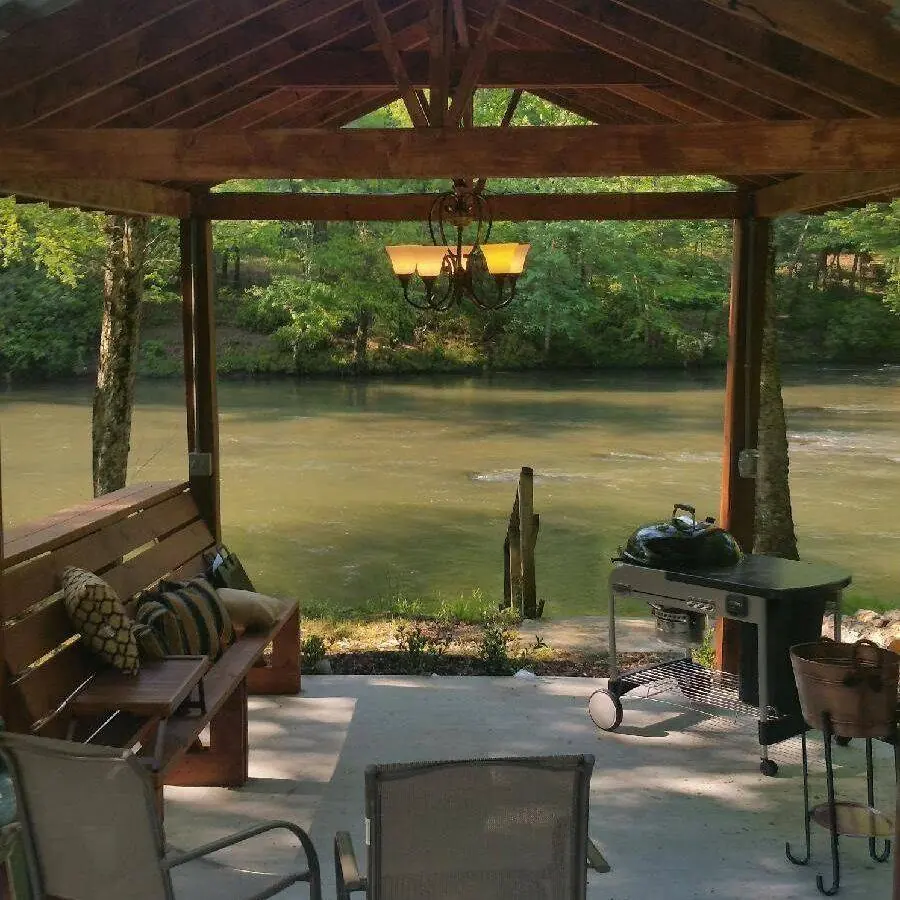 Timber-framed pavilion with a concrete patio beside a river